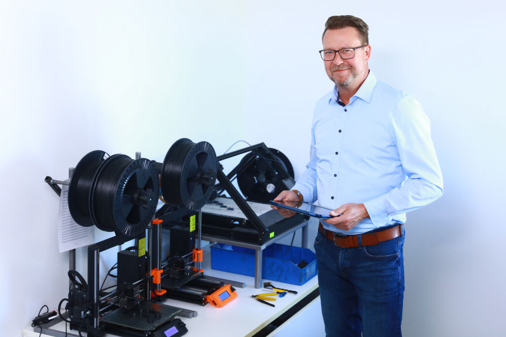 Gesch&auml;ftsf&uuml;hrer Sascha Kr&ouml;ner steht an einem 3D-Drucker