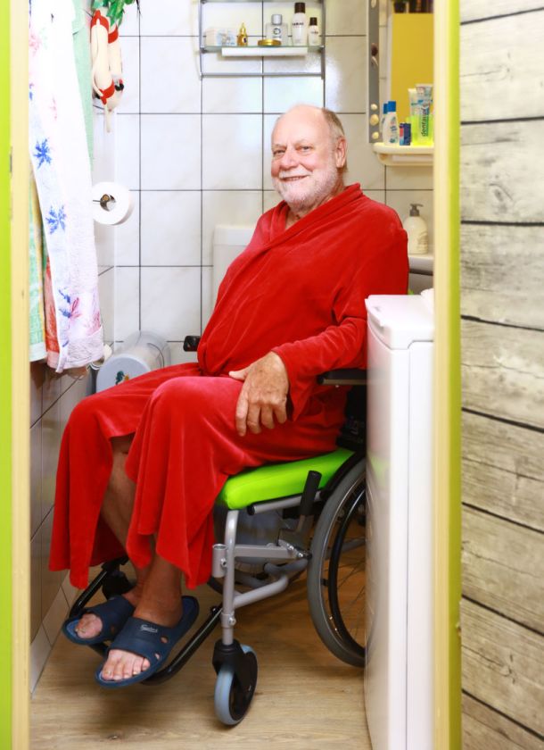 Mann im Rollstuhl kommt aus dem schmalen Badezimmer gefahren