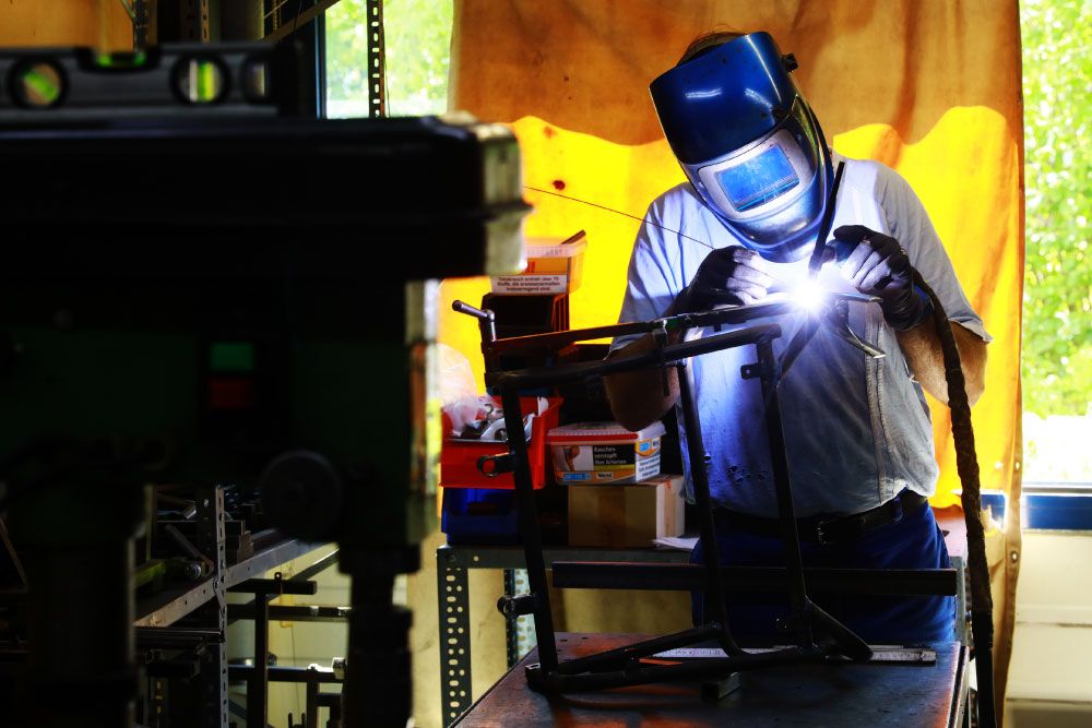 Schweißer fertigt Gestell für einen schmalen Zimmerrollstuhl