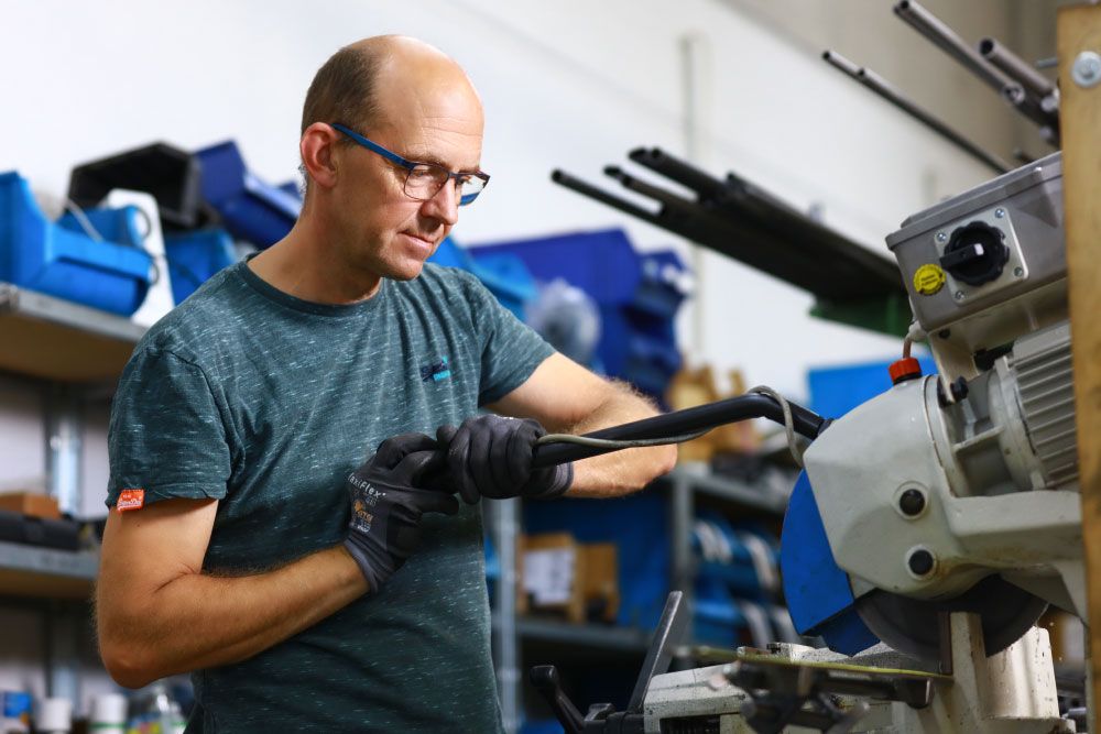 Per Hand fertigt ein Mitarbeiter die Einzelteile für einen individuellen, schmalen Zimmerrollstuhl